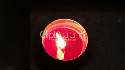 A red melting candle light inside a round glass