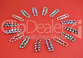 Paper clips in colors on red background