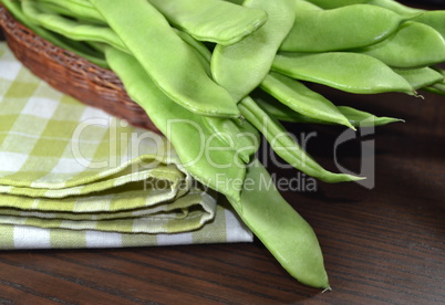 Raw green beans on a table cloth.