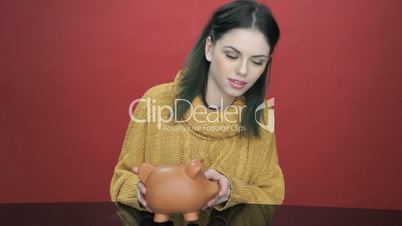 Pretty young woman shaking her piggy bank