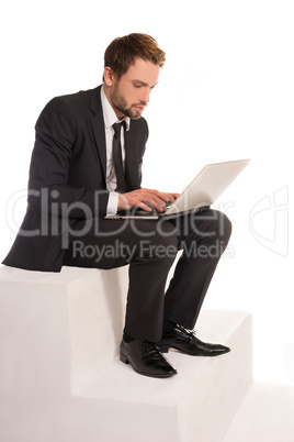 businessman sitting on a stair working on a laptop