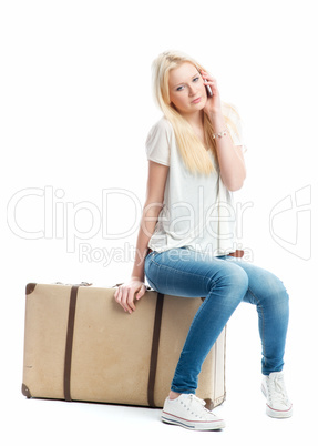 Mädchen sitzt auf Koffer und telefoniert