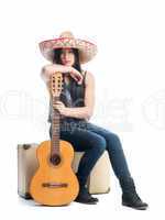 Mädchen mit Gitarre sitzt auf Koffer