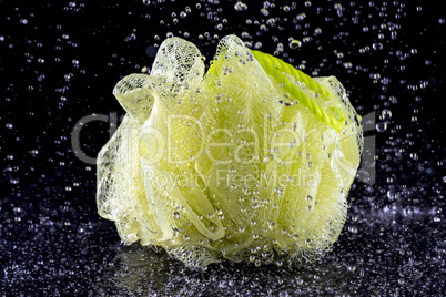 yellow bath sponge on black in water