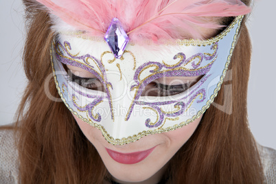 Beautiful teenage girl wearing carnival mask with pink feathers