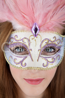 Beautiful teenage girl wearing carnival mask with pink feathers