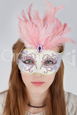 Beautiful teenage girl wearing carnival mask with pink feathers