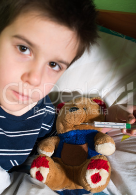 sick child in bed with teddy bear