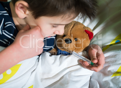 sick child in bed with teddy bear