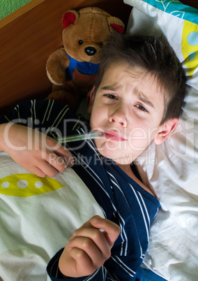 sick child in bed with teddy bear