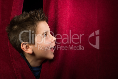 child appearing beneath the curtain