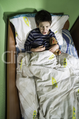 sick child in bed with teddy bear