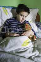 sick child in bed with teddy bear