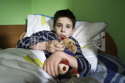 sick child in bed with teddy bear