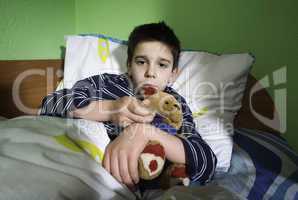 sick child in bed with teddy bear