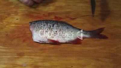 fisherman hands with knife hacking fish