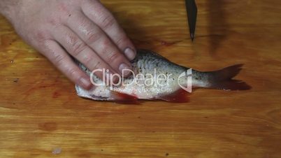 fisherman hands with knife hacking fish