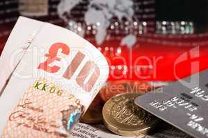 coins, credit cards and british pounds on newspaper