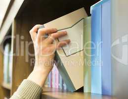 hand pulling a book off the shelf