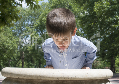 child drinking water from a fountain