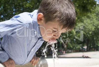 child drinking water from a fountain