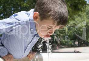 child drinking water from a fountain