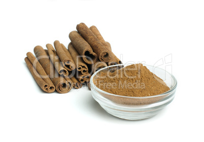 powdered cinnamon in bowl and cinnamon sticks