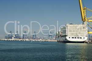 freighter in port being loaded with containers