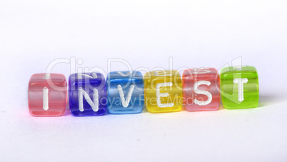 Text Invest on colorful wooden cubes