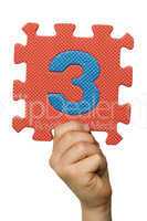 Children hand holding the number Three. White isolated number