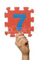 Children hand holding the number Seven. White isolated number