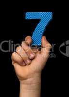 Children hand holding the number Seven