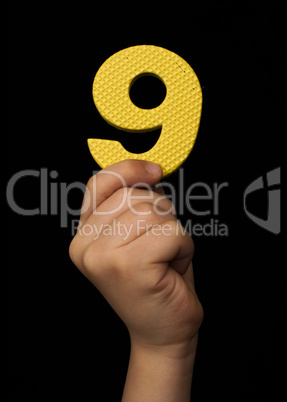 Children hand holding the number Nine