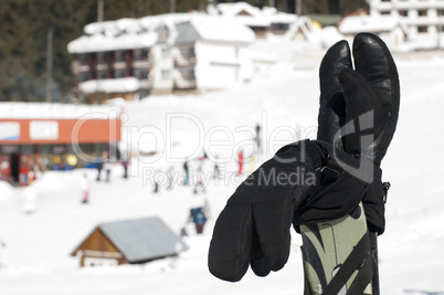 Ski gloves and sticks. Winter tourists on the background