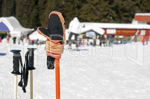Ski gloves and sticks. Winter tourists on the background