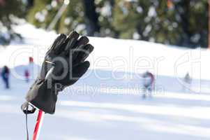Ski gloves and sticks. Winter tourists on the background