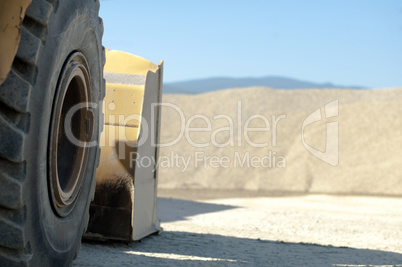 Tire backhoe close-up and piles of sand