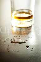Glass with whiskey and drops on the table