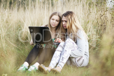 female friends with laptop outdoor