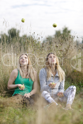 two playful girls juggling outdoors