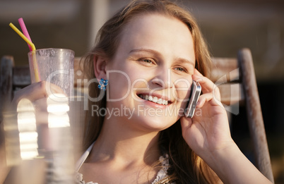 woman talking on her mobile drinking cocktail and smiling