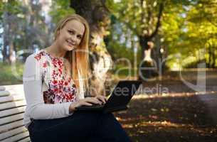 young woman using her laptop in the park