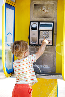 young boy talking to the phone in a booth