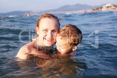 happy mother teaching her young son to swim