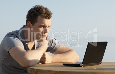 man looking to the display of small laptop computer
