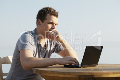 man typing on a small laptop computer