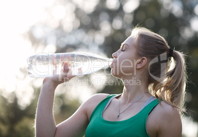 young woman drinking water after fitness