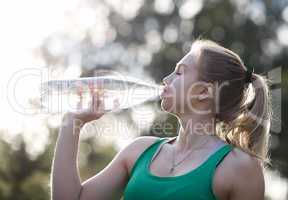 young woman drinking water after fitness