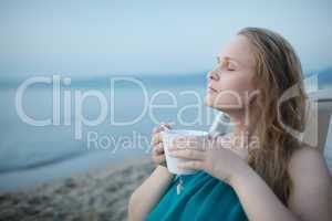 woman with closed eyes enjoying a cup of tea at the seaside