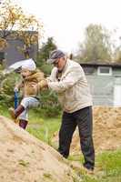 grandpa helps grandson to get on a sand hill
